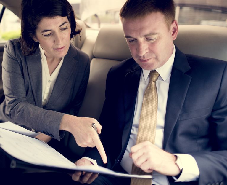 People Sitting in a Vehicle Looking at Paperwork